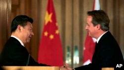 Presiden China Xi Jinping (kiri) berjabat tangan dengan PM Inggris David Cameron, dalam konferensi pers bersama di London (21/10). 