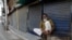 FILE - An Indian Muslim sits in front of closed shops during a coronavirus shutdown in Prayagraj, India, April 5, 2020. 