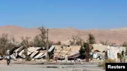 A man carries a bag as he walks along damaged houses in Duma neighbourhood in Damascus, Syria, Oct. 1, 2013. 
