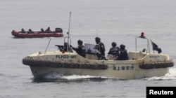 FILE - Anti-Terrorist Units of the Philippine and Japanese Coast Guards (R) prepare to target a vessel and engage the mock pirates during a combined maritime law enforcement exercise at a bay in Manila, May 6, 2015.