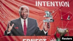 A child street vendor stands in front of a poster for Sierra Leone's ruling party presidential candidate Ernest Bai Koroma, Freetown, Nov. 16, 2012.