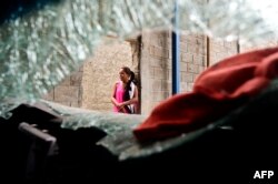 A woman stands next to a damaged car at a supermarket parking bay in Valencia, Carabobo State, Venezuela, May 5, 2017, the day after anti-government protesters looted stores, set fire to cars and clashed with police.