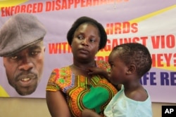 FILE - Sheffra Dzamara, wife of activist Itai Dzamara, holds her daughter and speaks to The Associated Press in Harare, March 8, 2016. Dzamara was pleading for the return of her activist husband, abducted by suspected state security agents.