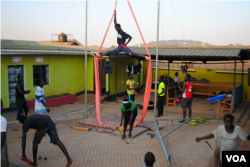 One of Hiccup Circus's senior aerialists practices his splits while jugglers and acrobats gather around to watch. (Elizabeth Paulat/VOA)