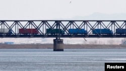 Trucks drive on the Friendship Bridge over the Yalu River which connects North Korea's Sinuiju to China's Dandong, April 11, 2013.