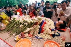 FILE - In this July 11, file photo, the body of Cambodian government critic Kem Ley is covered by the Cambodian \flag as flowers are placed during a funeral ceremony in Phnom Penh, Cambodia.