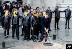 French President Emmanuel Macron lights up with children the Tomb of the Unknown Soldier under the Arc de Triomphe during ceremonies, Nov. 11, 2018 in Paris.