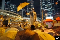 FILE - Protesters hold umbrellas on a main road in the occupied areas outside government headquarters in Hong Kong's Admiralty in Hong Kong, Oct. 9, 2014.