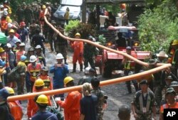Rescuer carry water pipe makes their way up at the entrance to a cave complex where 12 boys and their soccer coach were trapped inside when heavy rains flooded the cave, in Mae Sai, Chiang Rai province, in northern Thailand, July 4, 2018.