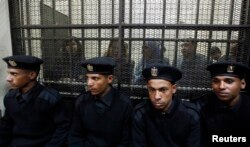 FILE - Some of the 14 Egyptian activists who were accused of working for unlicensed nongovernmental organizations (NGOs) and receiving illegal foreign funds stand in a cage during the opening of their trial in Cairo, Feb. 26, 2012.
