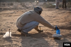 A forensic investigator brushes away soil from the top of a mass grave containing 17 bodies buried nearly 30 years ago in Berbera, Somaliland. (J. Patinkin/VOA)