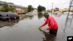 David Linnen takes a yard rake to clear drains in front of Winyah Apartments in Georgetown, S.C., Sunday, Oct. 4, 2015.