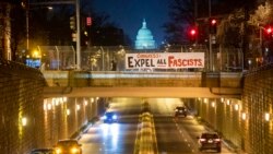 An activist with the group ShutDownDC takes a photo of a banner put up by the group calling on Congress to 'expel all fascists' on an overpass near the US Capitol in Washington on Jan. 5, 2022.