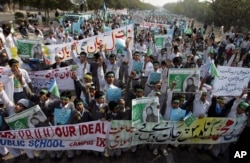 FILE - Students chant slogans while holding banners and posters showing Mumtaz Qadri, the alleged killer of Punjab governor Salman Taseer, during a rally to protest against any attempts to modify blasphemy laws, in Karachi, Pakistan, Jan. 20, 2011.