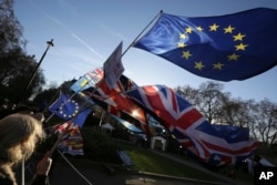 Anti-Brexit protesters wave flags outside the Houses of Parliament, in London, Dec. 12, 2018.