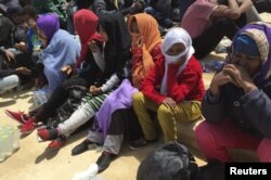 FILE - Illegal migrants who attempted to sail to Europe sit on the shore after their boat was intercepted at sea by the Libyan coast guard in Khoms, Libya, May 6, 2015.