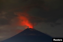 Lava, inside the crater of Mount Agung, reflects off the volcano's ash and clouds, while it erupts, as seen from Amed, Karangasem Regency, Bali, Indonesia, Nov. 30, 2017.