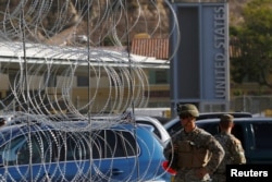 U.S. Marines stand guard next to a barricade with concertina wire at the border between Mexico and the U.S., in preparation for the arrival of migrants, in Tijuana, Mexico, Nov. 13, 2018.