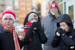 University of Nebraska students sip complementary hot chocolate as they wait in freezing temperatures to be admitted to Pinnacle Bank Arena for an NCAA college basketball game against Wisconsin, in Lincoln, Neb., Jan. 29, 2019.