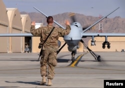 A FILE - US airman guides a US Air Force MQ-9 Reaper drone as it taxis to the runway at Kandahar Airfield, Afghanistan.