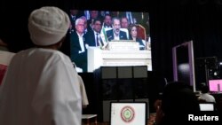 Members of the media watch Syrian National Coalition (SNC) President Mouaz al-Khatib during a live address during the opening of the Arab League summit in Doha, Mar. 26, 2013.
