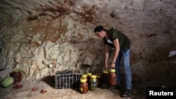 A man holds pickled vegetables in an underground cave in Idlib, Syria, Sept. 3, 2018. The city is bracing for an attack by Syrian forces.