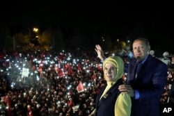 FILE - Turkey's President Recep Tayyip Erdogan and his wife, Emine Erdogan, pose for photos with cheering supporters in the background after unofficial referendum results were announced, in Istanbul, late Sunday, April 16, 2017.