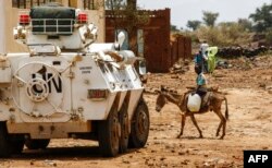 A Sudanese boy rides a donkey past a UN-African Union mission in Darfur (UNAMID) armoured vehicle in the war-torn town of Golo in the thickly forested mountainous area of Jebel Marra in central Darfur.