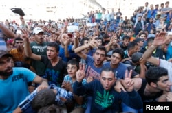 Migrants wave their train tickets outside the main Eastern Railway station in Budapest, Hungary, Sept. 1, 2015.