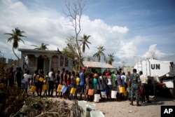 United Nations police from Bangladesh deliver drinking water to residents of Sous-Roche village, outside Les Cayes, Haiti, Oct. 11, 2016.