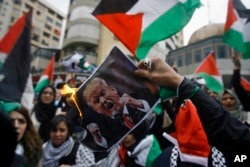 Lebanese and Palestinians students burn a poster of U.S. President Donald Trump as they take part in a protest, in the southern port city of Sidon, Lebanon, Dec. 7, 2017.