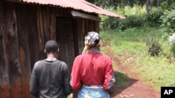 A mother walks beside her mentally disabled 14-year-old daughter who was raped by a neighbor in Kabazi, Kenya, August 24, 2010.