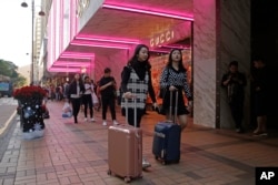 FILE - Chinese tourists walk on Canton Road, the one-stop-shop street of high-end brands in Hong Kong, Nov. 29, 2018.
