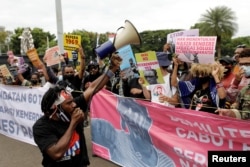 Aktivis Papua memegang plakat dalam peringatan peringatan deklarasi kemerdekaan Papua Barat dari penjajahan Belanda, di luar kompleks Monumen Nasional di Jakarta, 1 Desember 2021. (Foto: REUTERS/Willy Kurniawan)