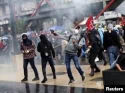Demonstrators throw stones in clashes with riot police that occurred during the march in Mexico City, Sept. 26, 2015.