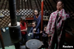 FILE - The wife and children of Setevdorj Myagmartsogt gather around their new coal burning stove while talking to reporters in their tent-like ger home in Ulaanbaatar, Mongolia, Jan. 29, 2017.
