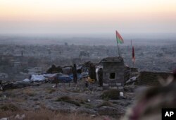 Kurdish fighters watch in the early morning as they fight against the Islamic State group in Sinjar, Iraq, Friday, Nov. 13, 2015.