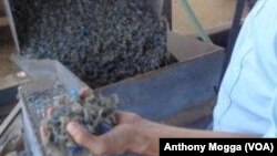 Olivier Snowden, an advisor at the Environment Rehabilitation Program (ERP) holds up a handful of shredded plastic made from bottles collected by local women.