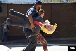 FILE - A Latino couple walk with a pinata of Republican presidential candidate Donald Trump in Los Angeles, Sept. 23, 2015.