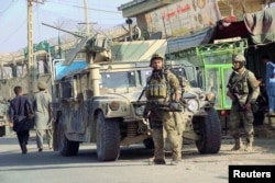 Afghan security forces keep watch in front of their armored vehicle in Kunduz city, Afghanistan, Oct. 4, 2016.