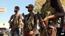 FILE - In this file image made from video posted online Oct. 16, 2016, by Qasioun News Agency, Turkish-backed Syrian opposition forces patrol in Dabiq, Syria.