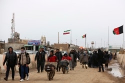 FILE - Afghans return to Afghanistan at the Islam Qala border with Iran, in the western Herat province, Feb. 20, 2019.