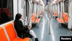 Une femme portant un masque protecteur se trouve à l'intérieur d'un métro vide, à Rome,, pendant le confinement national imposé pour ralentir l'apparition d'un coronavirus en Italie, le 12 mars 2020. REUTERS / Remo Casilli