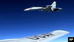 In this image released by the U.S. Air Force, a U.S. RC-135 flying in international airspace over the Baltic Sea is intercepted by a Russian SU-27 jet, June 19, 2017. The Russian military said it scrambled a fighter jet to intercept and escort a U.S. strategic bomber flying over the Baltic along the Russian border. 