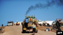 FILE - Syrian internally displaced children jump on the back of a truck at the Atme refugee camp, along the Turkish border in the northwestern Syrian province of Idlib. 
