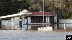 A Merry Christmas sign is mostly submerged by floodwaters from the Pea River, Dec. 26, 2015 in Elba, Ala. 