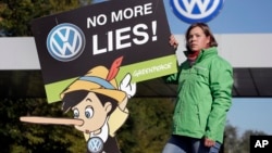 An activist with the environmental group Greenpeace protests Volkswagen emissions rigging. She stands outside a VW factory in Wolfsburg, Germany, Sept. 25, 2015.
