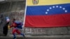 Un niño vestido como "SuperBigote" corre frente a una bandera venezolana en el barrio de Catia en Caracas, el 28 de febrero de 2022. 