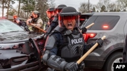 Police officers take cover as they clash with protesters after an officer shot and killed a black man in Brooklyn Center, Minneapolis, April 11,2021.