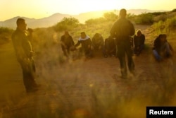 U.S. Border Patrol agents detain migrants who attempted to cross the U.S.-Mexico border undetected in a desert area outside Sunland Park, New Mexico, on June 23 2023.